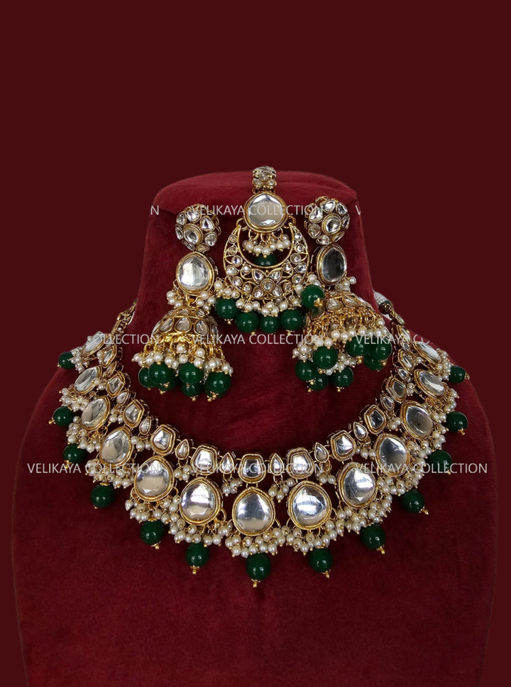 Gold and green kundan necklace set with earrings & tikka for Indian weddings.